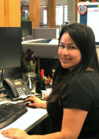 LTD employee Beatriz works at desktop computer in the business services department.