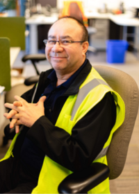 LTD employee Ceasar works at desktop computer wearing a reflective safety vest.