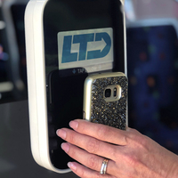 person holds mobile phone up to electronic fare validator