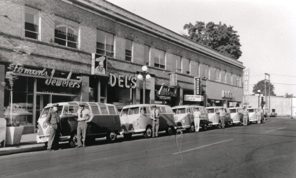 black and white photo of a line of VW busses waiting for passengers