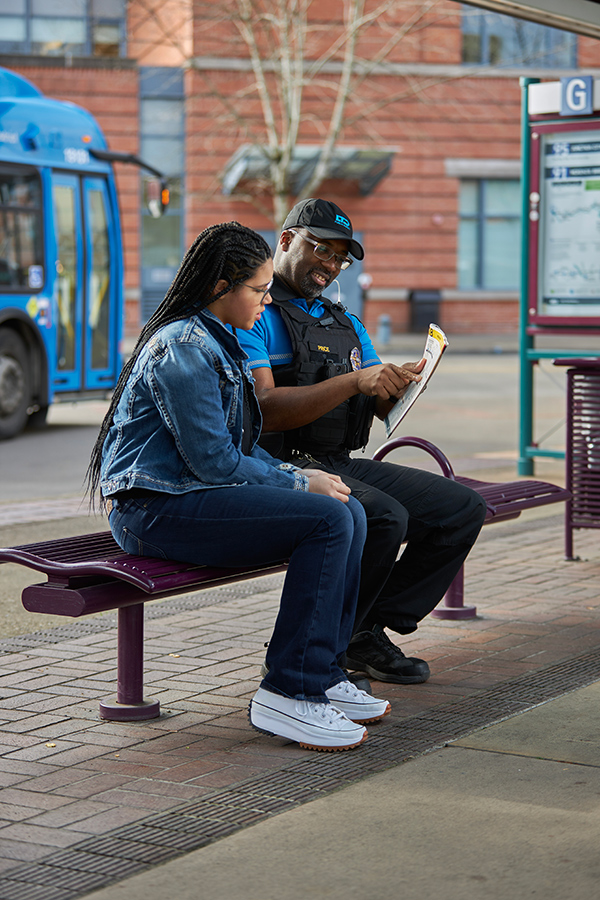 safety officer sitting with passenger at a bus stop