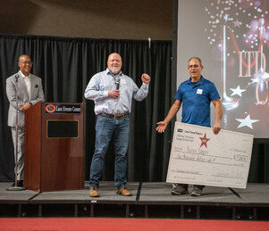 Kerry Cooper employee of the year holding a large check