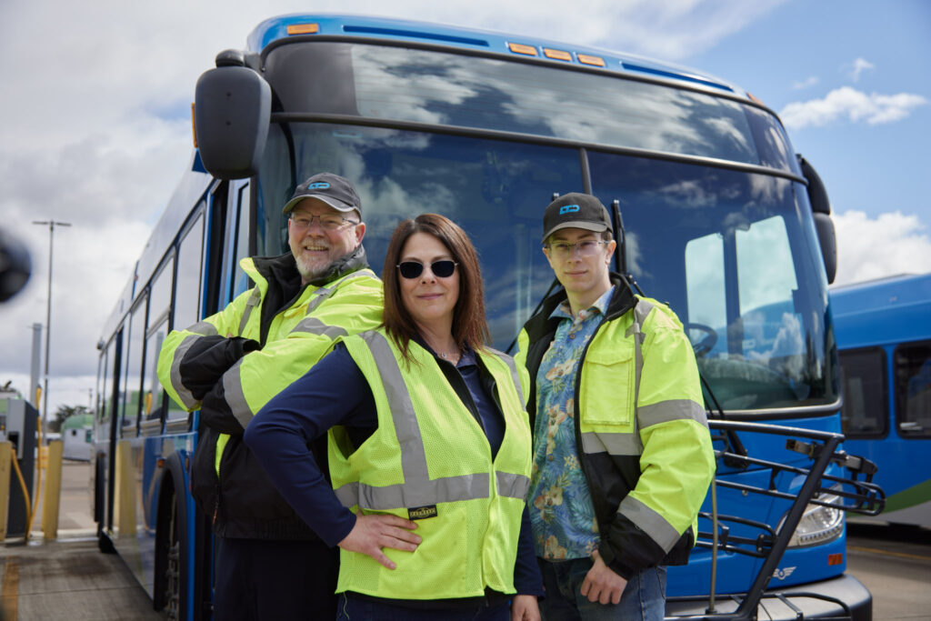 three people standing in front of bus