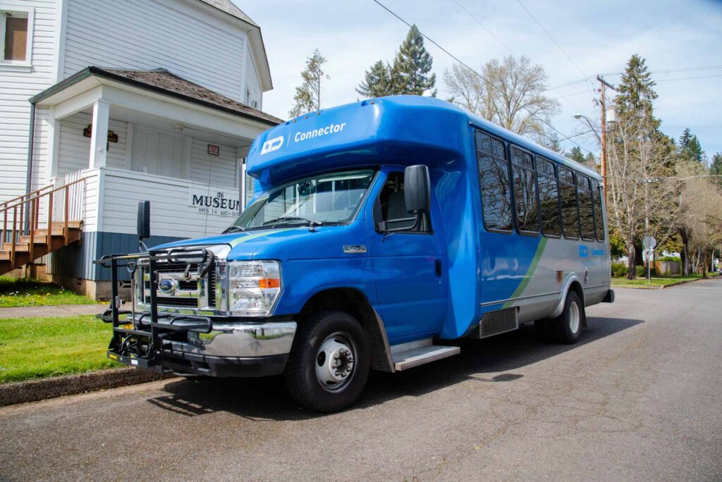 A blue IC Connector shuttle bus parked on a residential street near a white building labeled "Museum.