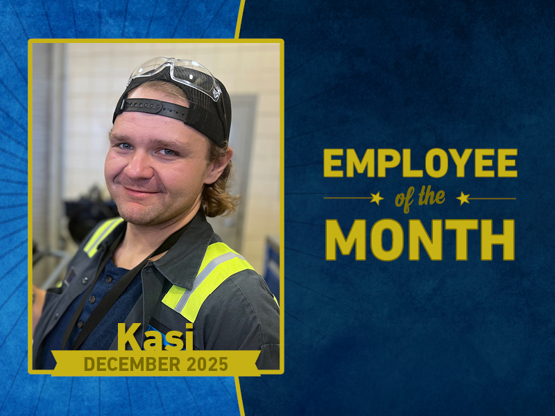 Man in safety gear smiles at the camera next to a sign that reads 