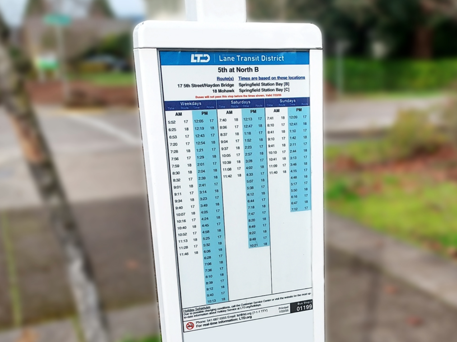Bus stop sign showing Lane Transit District schedule for Route 11 at 5th at North B, with weekday, Saturday, and Sunday departure times listed.