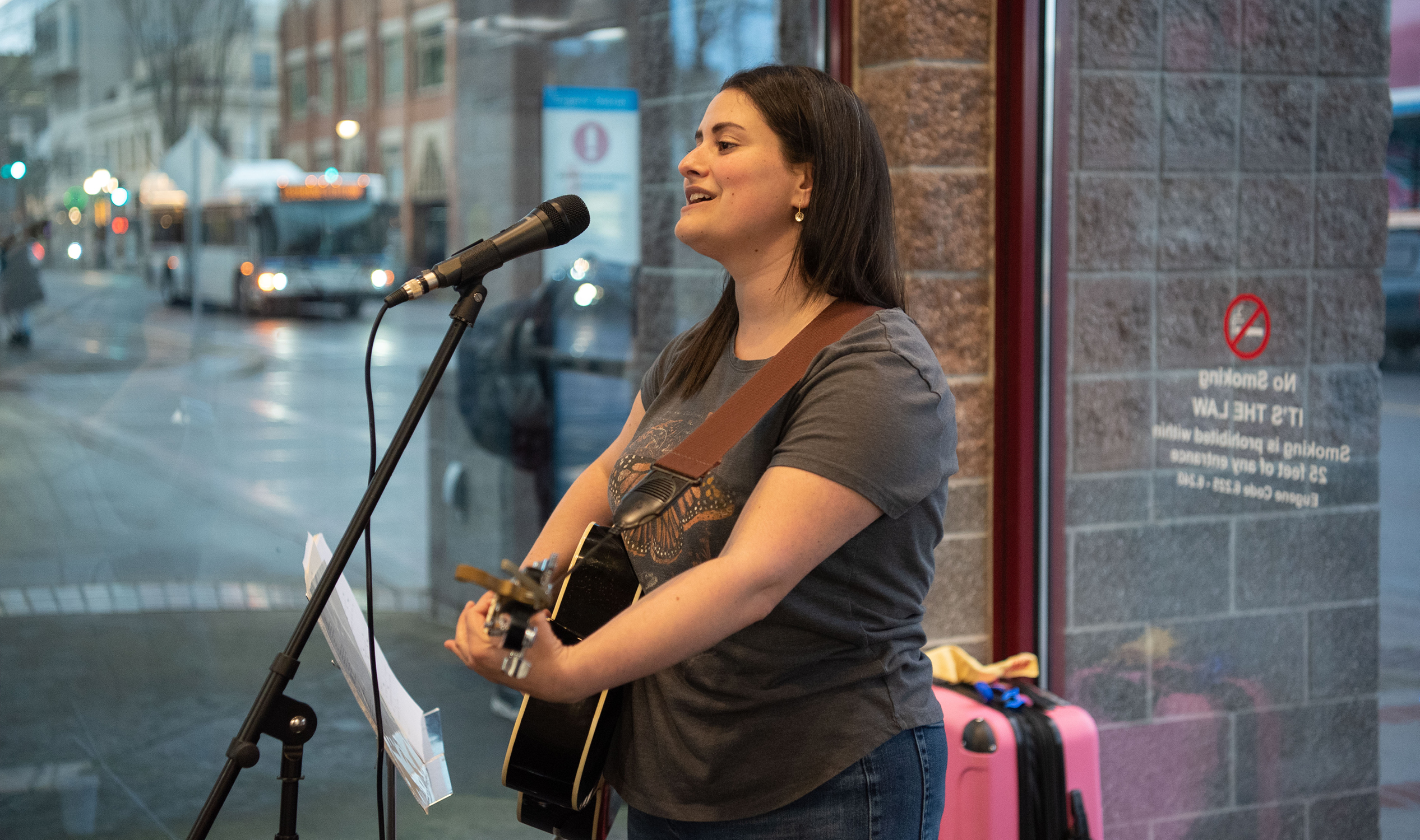 An On the Move music performance of a woman singing and playing guitar in Eugene Station.
