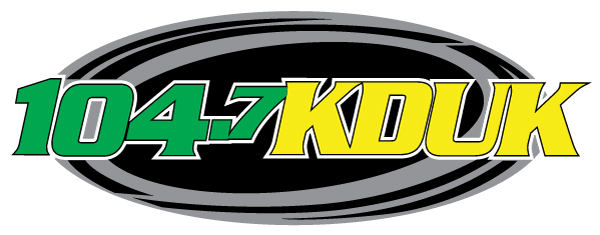 Logo for radio station 104.7 KDUK with green and yellow text inside a black oval.